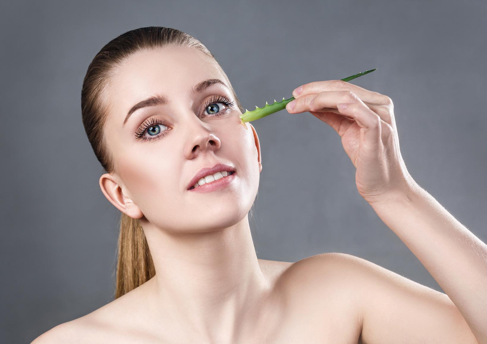 Young woman uses aloe vera oil for skin.