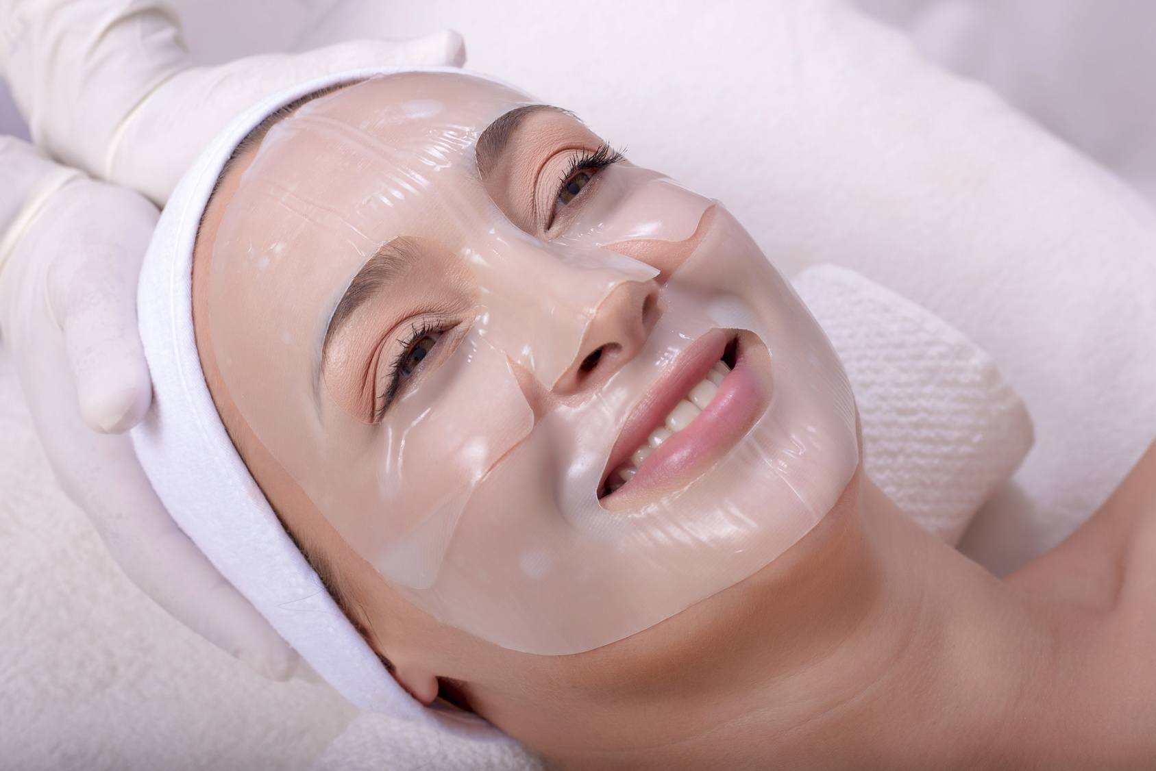 Portrait of beautiful smiling woman with skin mask on her face