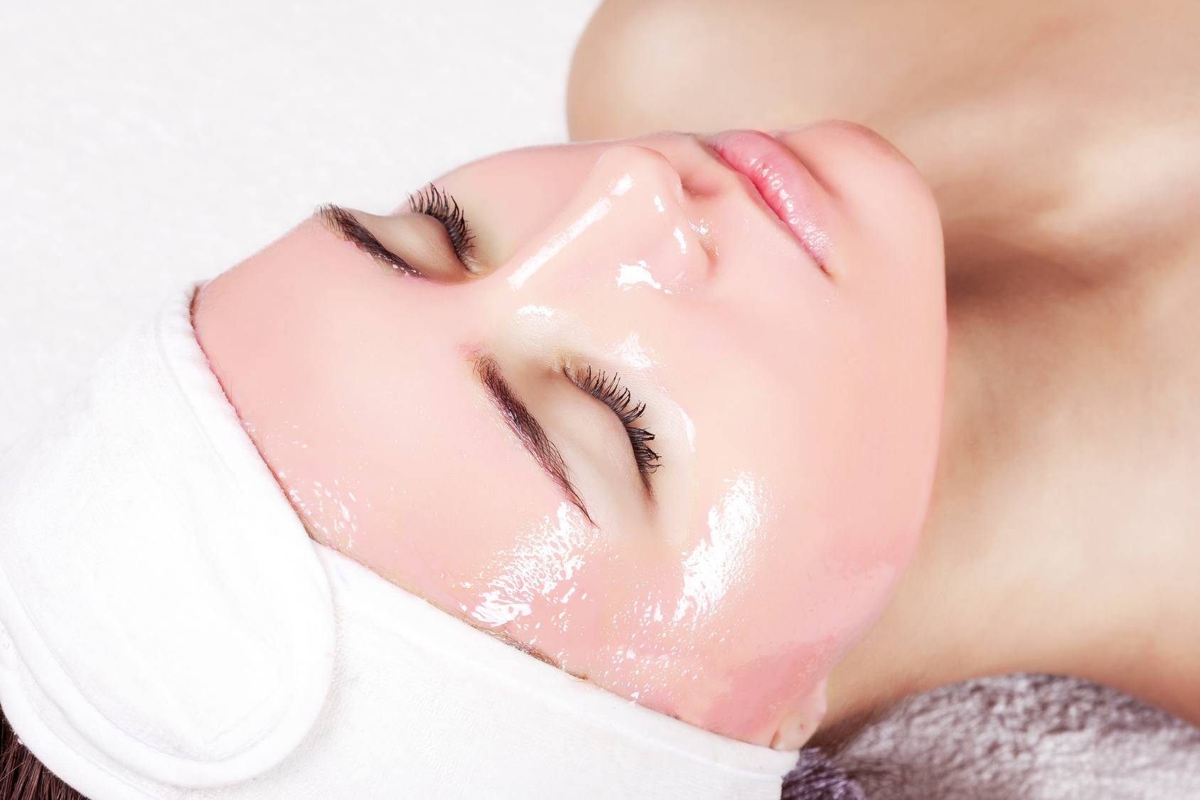 Young beautiful woman with moistening strawberry facial mask at beauty salon.
